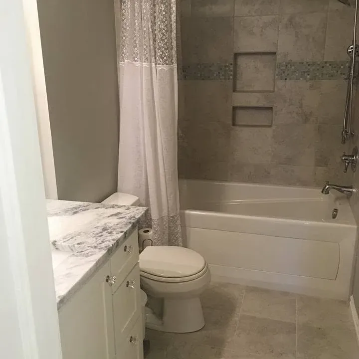 Small bathroom with tub, toilet, marble vanity, shower curtain, C&A Roofing & Construction