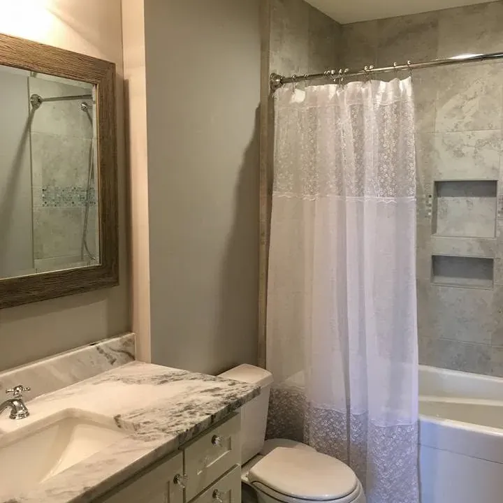 Bathroom with marble vanity, mirror, toilet, curtain tub, C&A Roofing & Construction