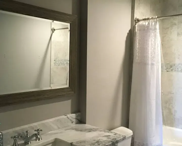 Vanity with marble top, toilet, and curtain shower, C&A Roofing & Construction