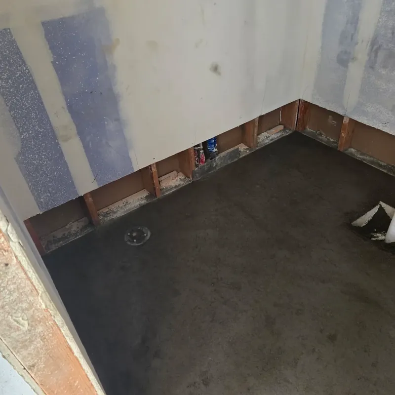 Gutted bathroom floor with shower pan prep, bare walls, C&A Roofing & Construction
