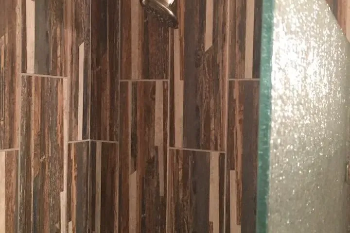 Close-up of wood-look tile shower wall and glass, C&A Roofing & Construction