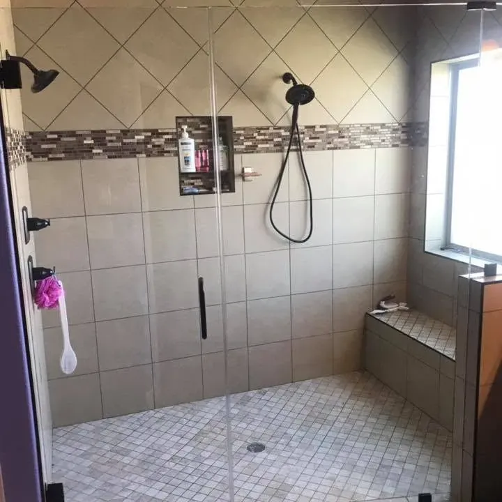 Tiled walk-in shower with frameless glass door and bench, C&A Roofing & Construction