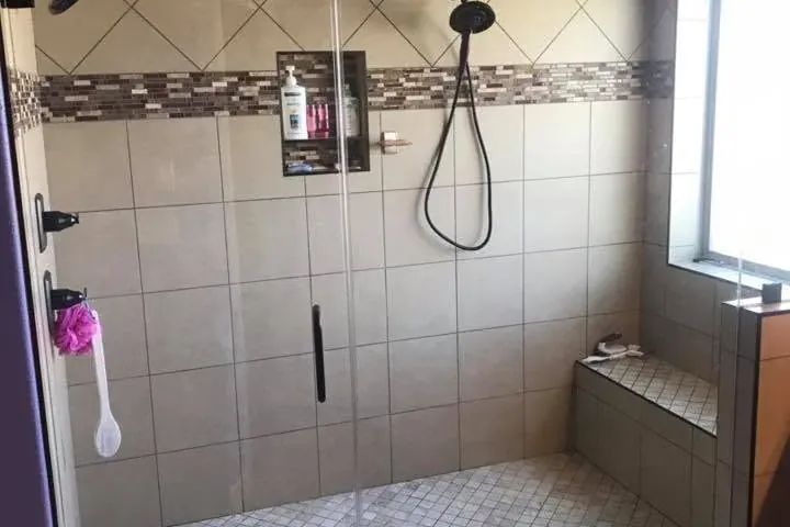 Tiled walk-in shower with frameless glass door and bench, C&A Roofing & Construction