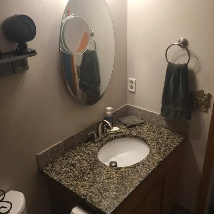 Granite vanity with sink, oval mirror, towel ring, C&A Roofing & Construction