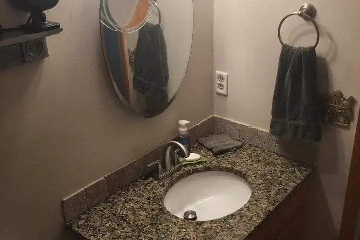 Granite vanity with sink, oval mirror, towel ring, C&A Roofing & Construction