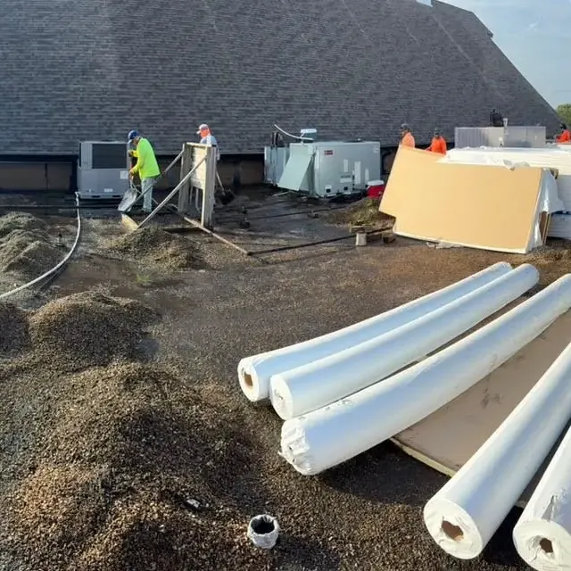 Flat roof tear-off with insulation rolls and crew, C&A Roofing & Construction