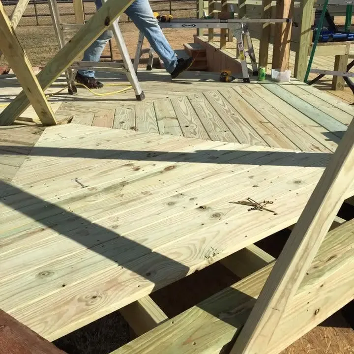 Wood deck with steps, workers' legs at top, C&A Roofing & Construction