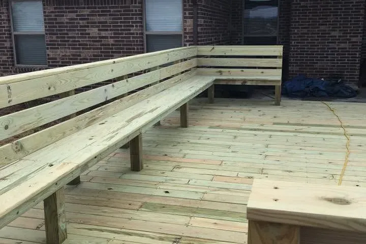 New wood deck with long built-in benches by brick house, C&A Roofing & Construction
