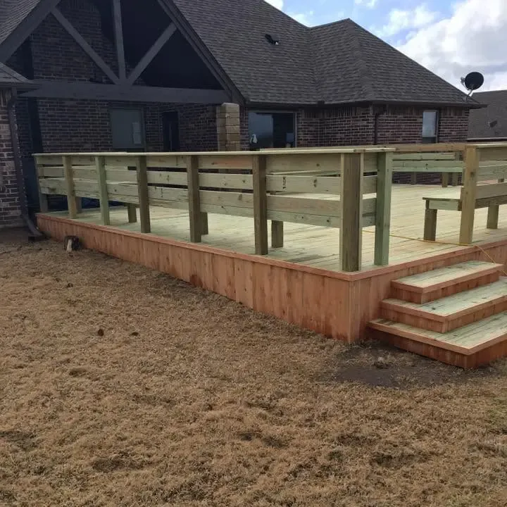 New raised wood deck with railing and steps behind brick house, C&A Roofing & Construction