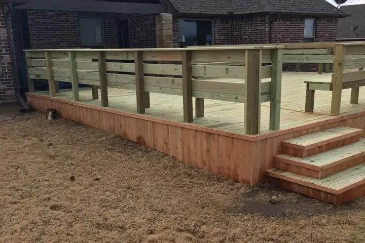 New raised wood deck with railing and steps behind brick house, C&A Roofing & Construction