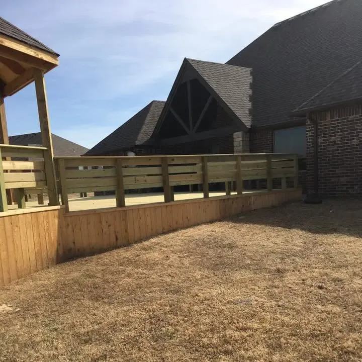 New raised wood deck with railing behind brick house, C&A Roofing & Construction