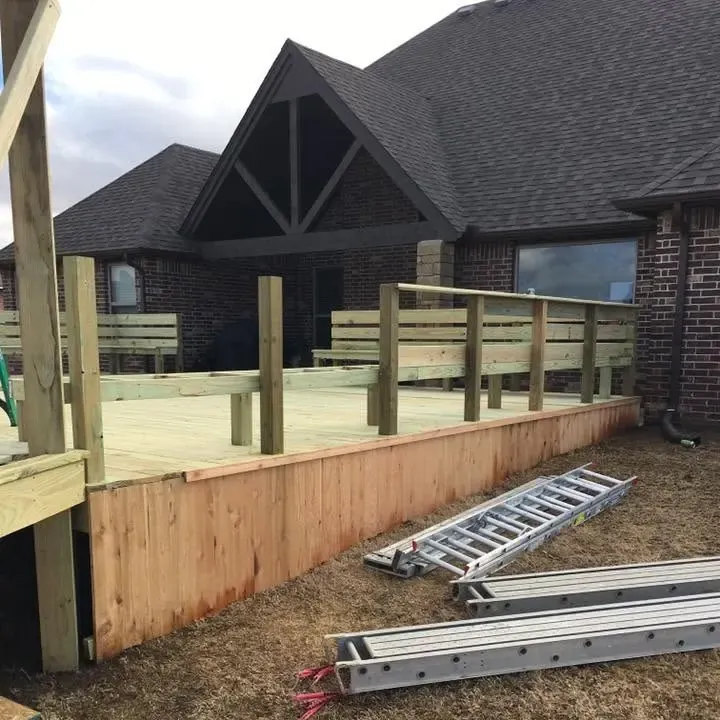 New deck railing behind house, ladders on lawn, C&A Roofing & Construction