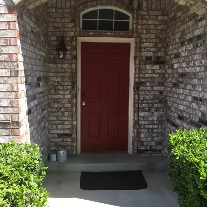 Freshly painted red front door in brick archway, C&A Roofing & Construction