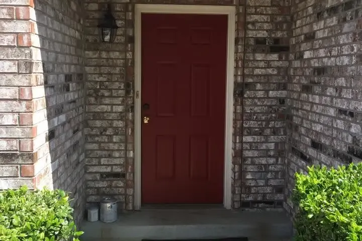 Freshly painted red front door in brick archway, C&A Roofing & Construction