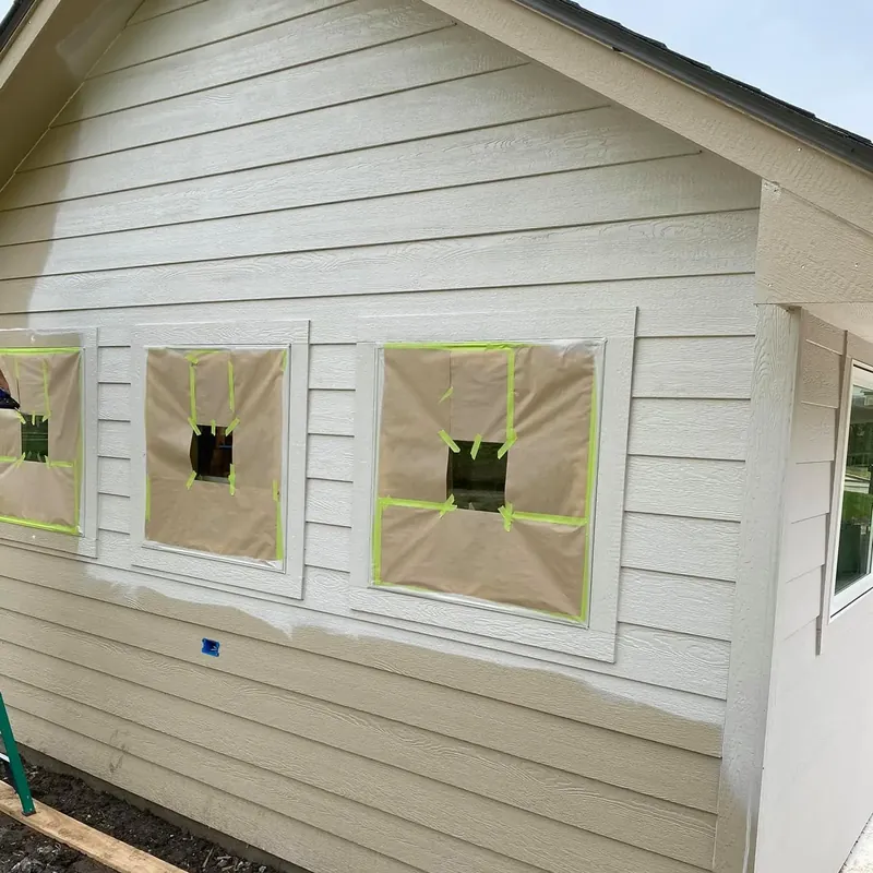 Siding prepped for paint with windows masked off, C&A Roofing & Construction