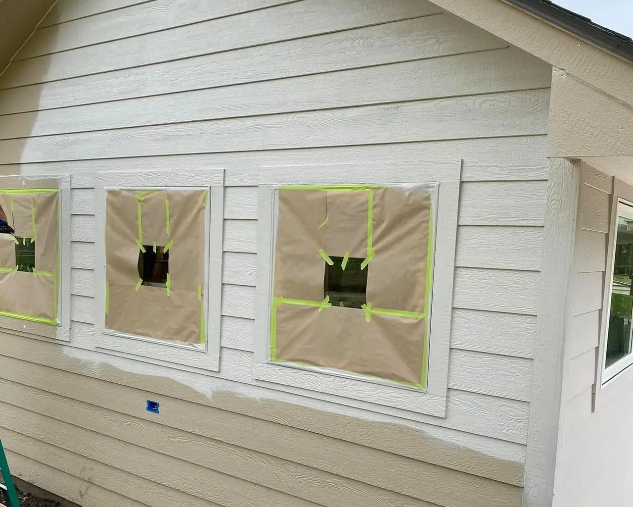 Siding prepped for paint with windows masked off, C&A Roofing & Construction