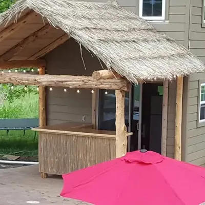 Thatched roof outdoor tiki bar with pink umbrella, C&A Roofing & Construction