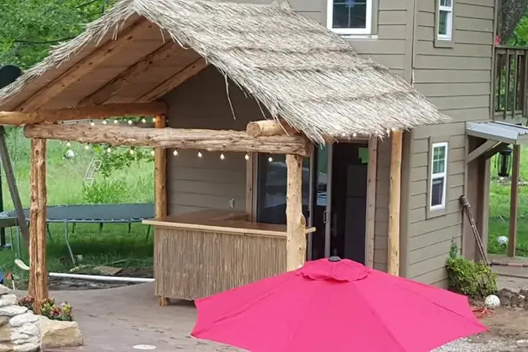 Thatched roof outdoor tiki bar with pink umbrella, C&A Roofing & Construction