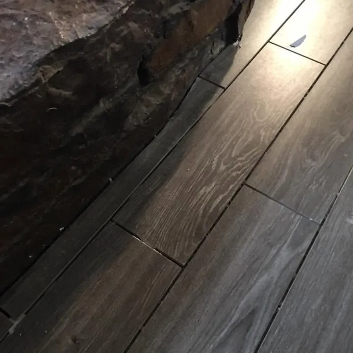 Dark wood-look tile floor meeting stone feature wall, C&A Roofing & Construction