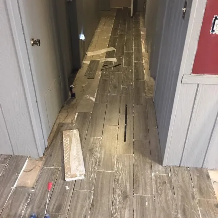 Wood-look tile being laid in narrow hallway, C&A Roofing & Construction
