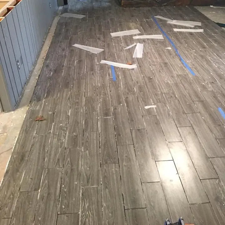 Gray wood-look tile floor in living room with scraps, C&A Roofing & Construction