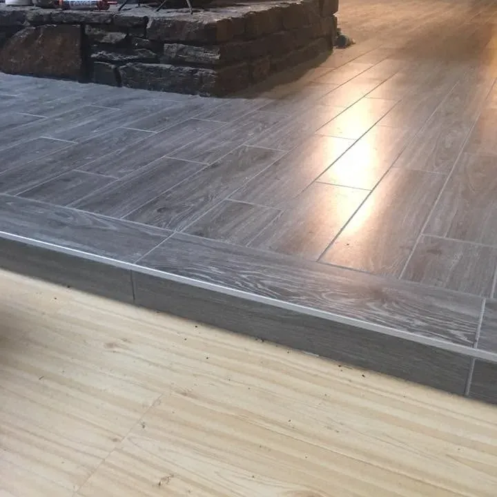 Gray wood-look tile transitioning to light hardwood floor, C&A Roofing & Construction