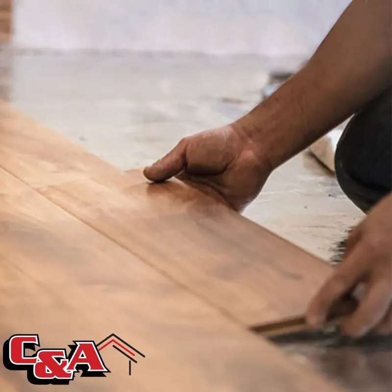 Hand laying laminate plank close-up, worker installing, C&A Roofing & Construction