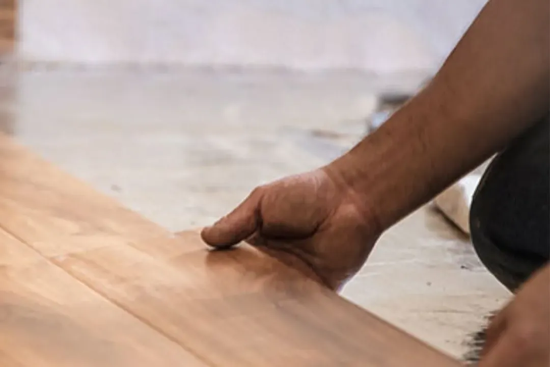 Hand laying laminate plank close-up, worker installing, C&A Roofing & Construction