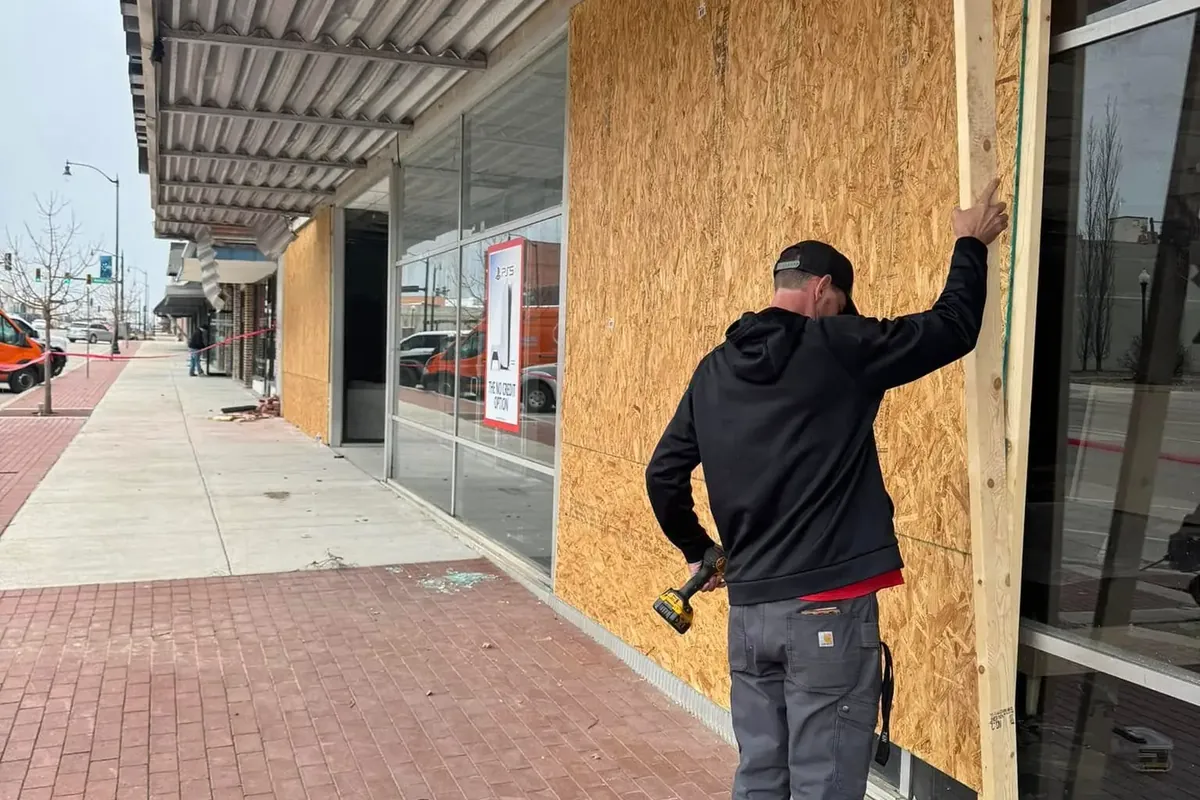 Worker boarding up damaged storefront with plywood, C&A Roofing & Construction