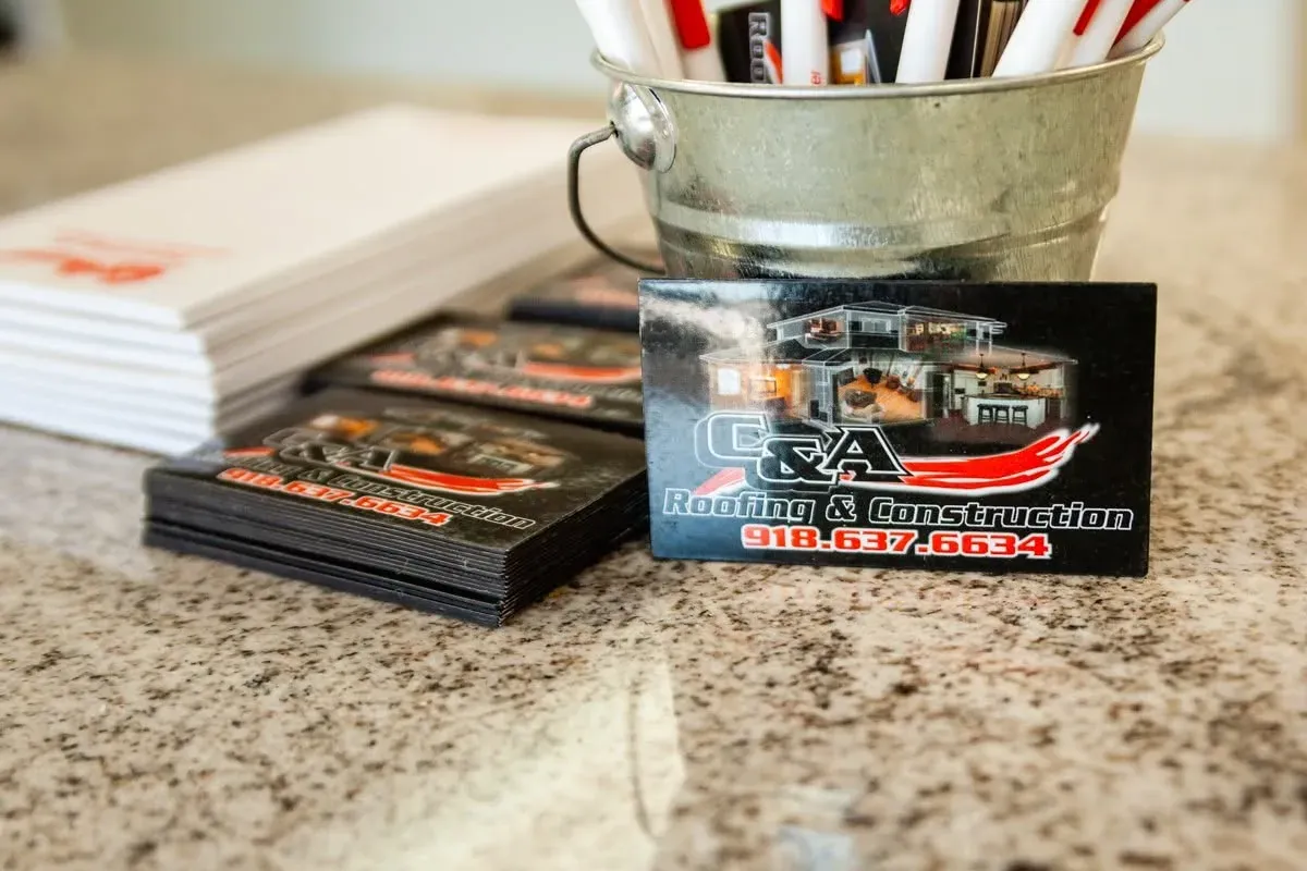 Business cards and branded pens on granite counter, C&A Roofing & Construction