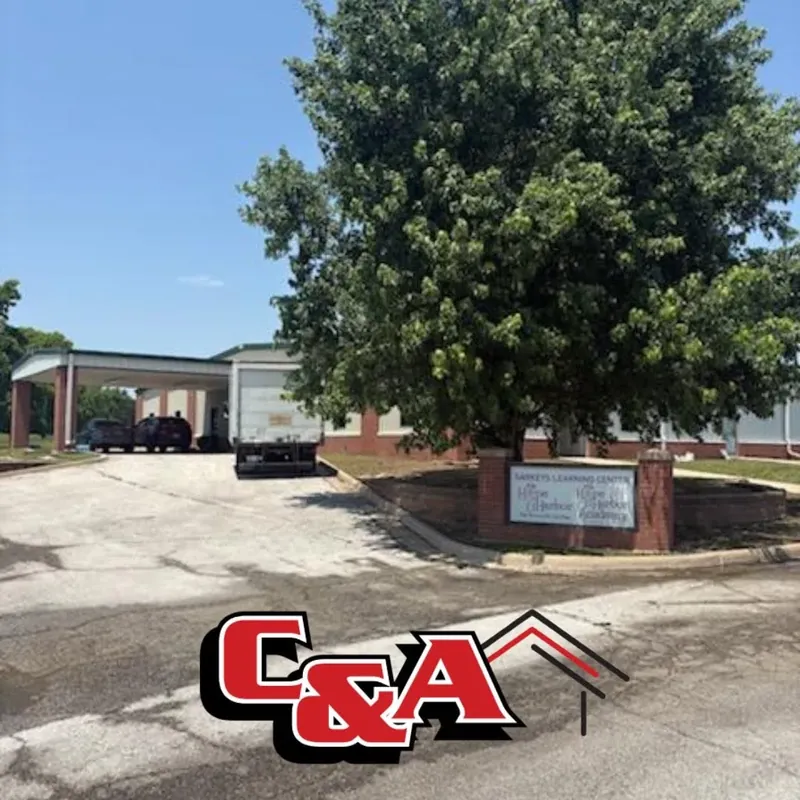 Commercial building entrance sign behind large tree, C&A Roofing & Construction