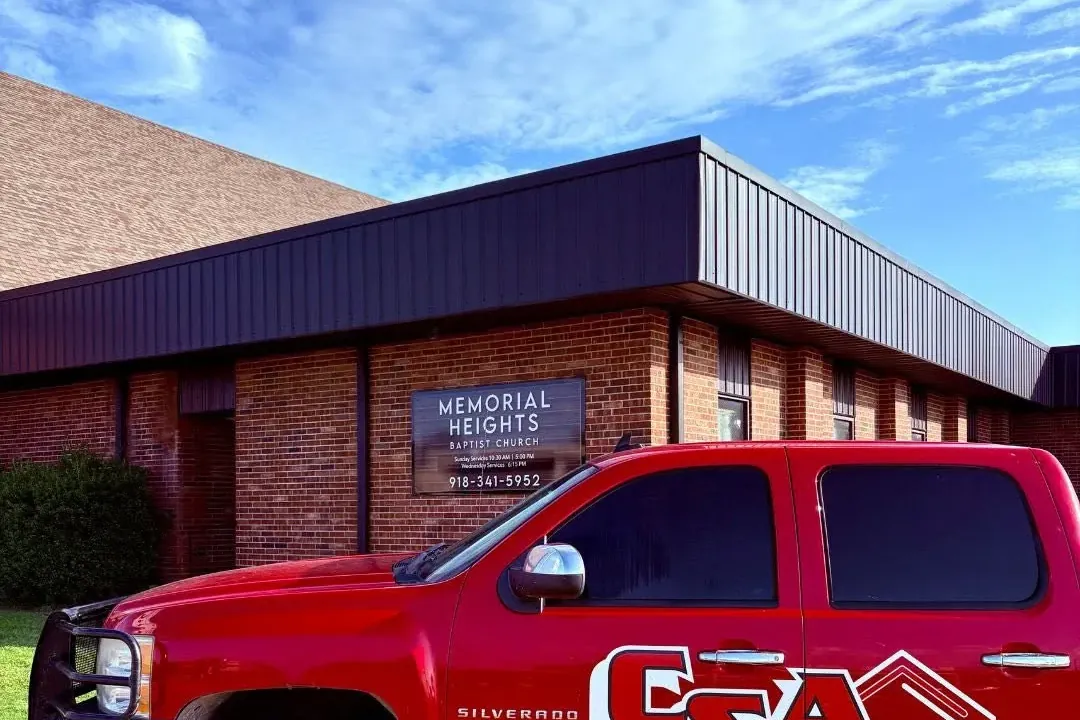 Red C&A branded pickup truck in front of brick church office, C&A Roofing & Construction