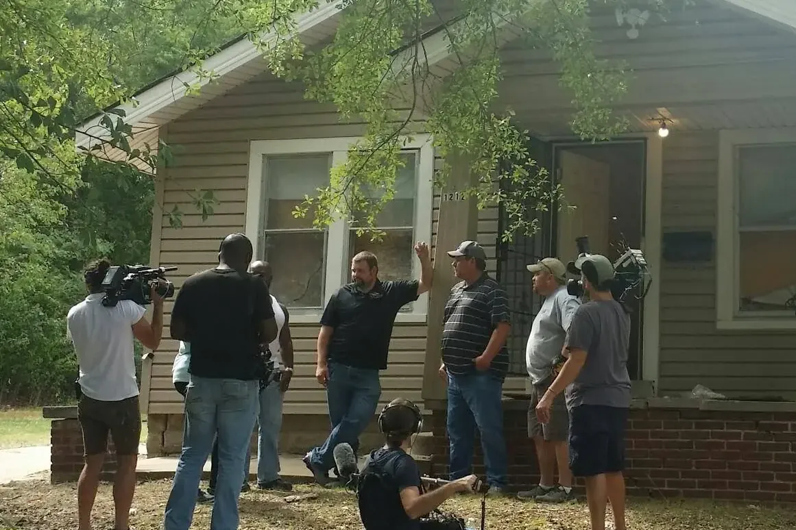 Film crew with cameras filming people at small house, C&A Roofing & Construction