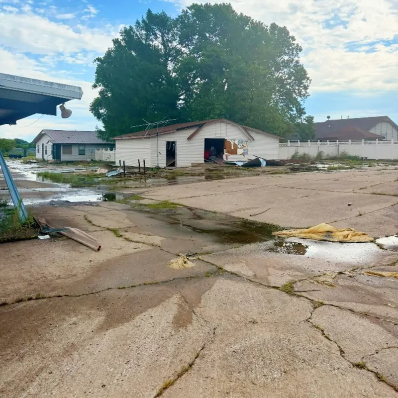 Cracked lot with standing water and damaged outbuilding, C&A Roofing & Construction