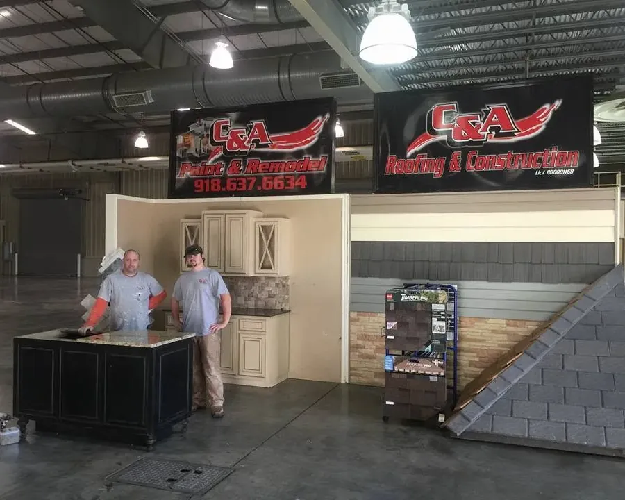 Trade show booth with kitchen display and two staff, C&A Roofing & Construction