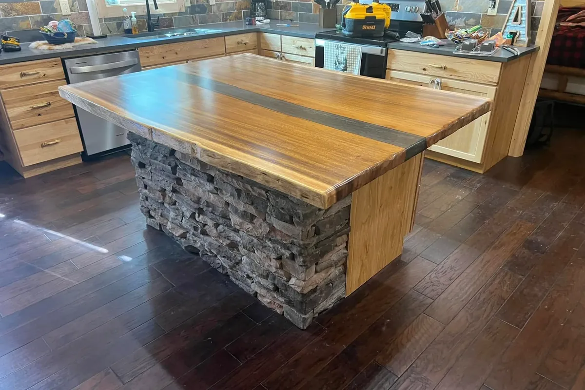 Live-edge wood island with stacked stone base, wider angle, C&A Roofing & Construction