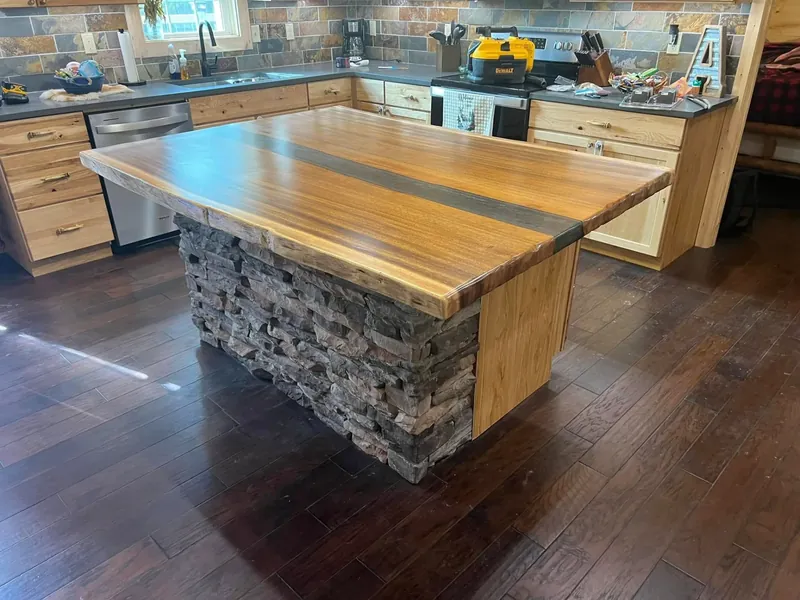 Live-edge wood island with stacked stone base, wider angle, C&A Roofing & Construction