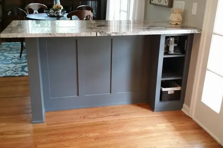 Gray paneled island with granite top on hardwood floor, C&A Roofing & Construction