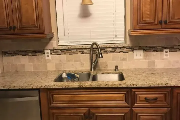 Wood cabinets, granite counter and sink under window, C&A Roofing & Construction
