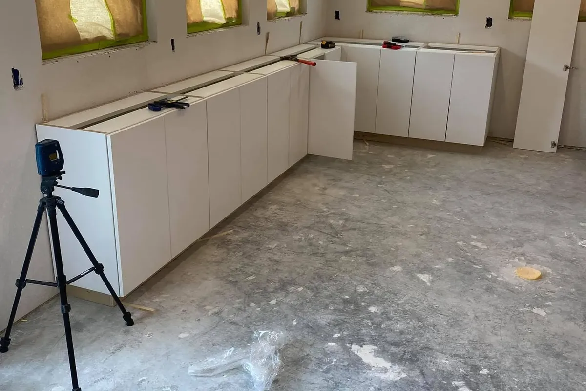 Base cabinets being installed in empty kitchen on bare slab, C&A Roofing & Construction