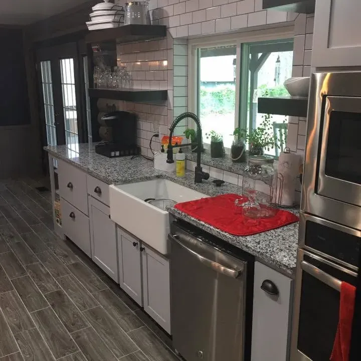 Finished kitchen with farmhouse sink, subway tile, floating shelves, C&A Roofing & Construction