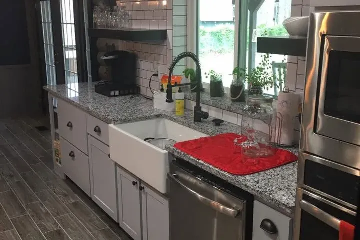 Finished kitchen with farmhouse sink, subway tile, floating shelves, C&A Roofing & Construction