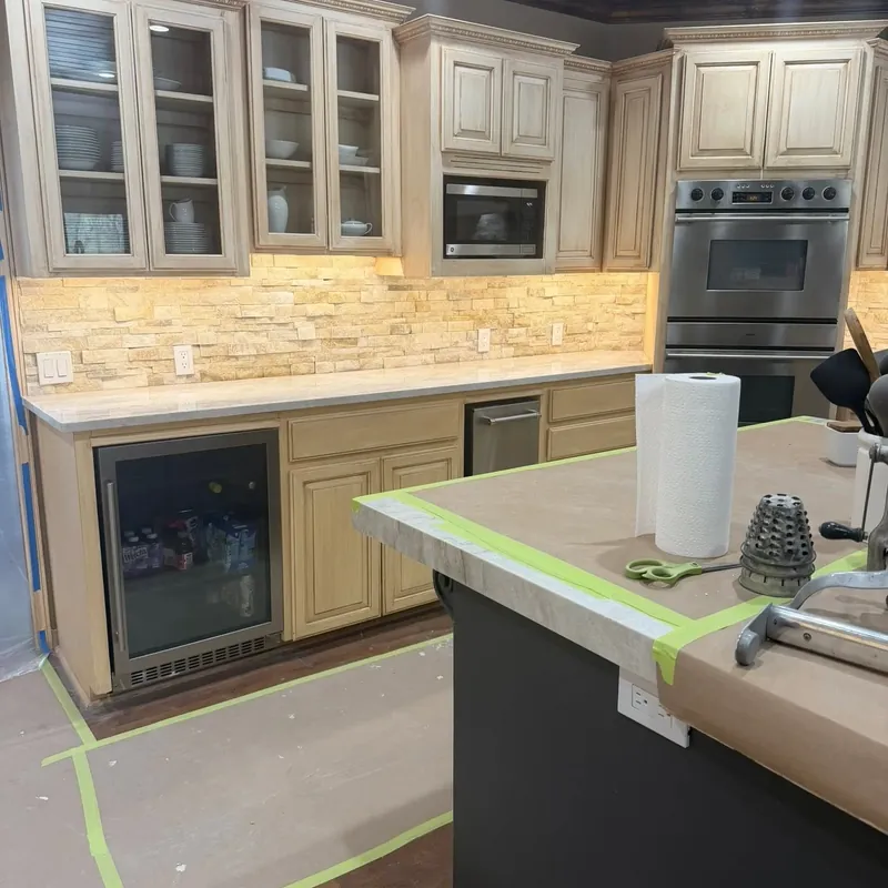 Cream cabinets, glass uppers, stone backsplash and dark island, C&A Roofing & Construction