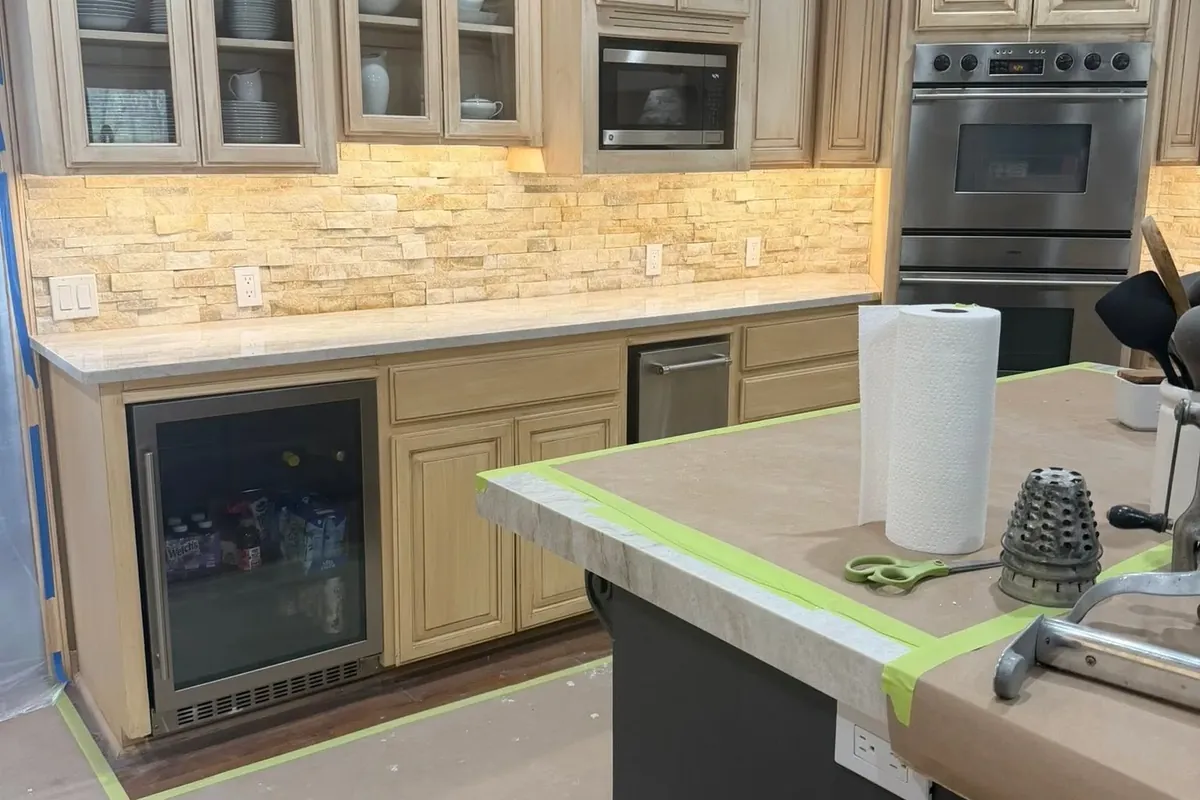 Cream cabinets, glass uppers, stone backsplash and dark island, C&A Roofing & Construction