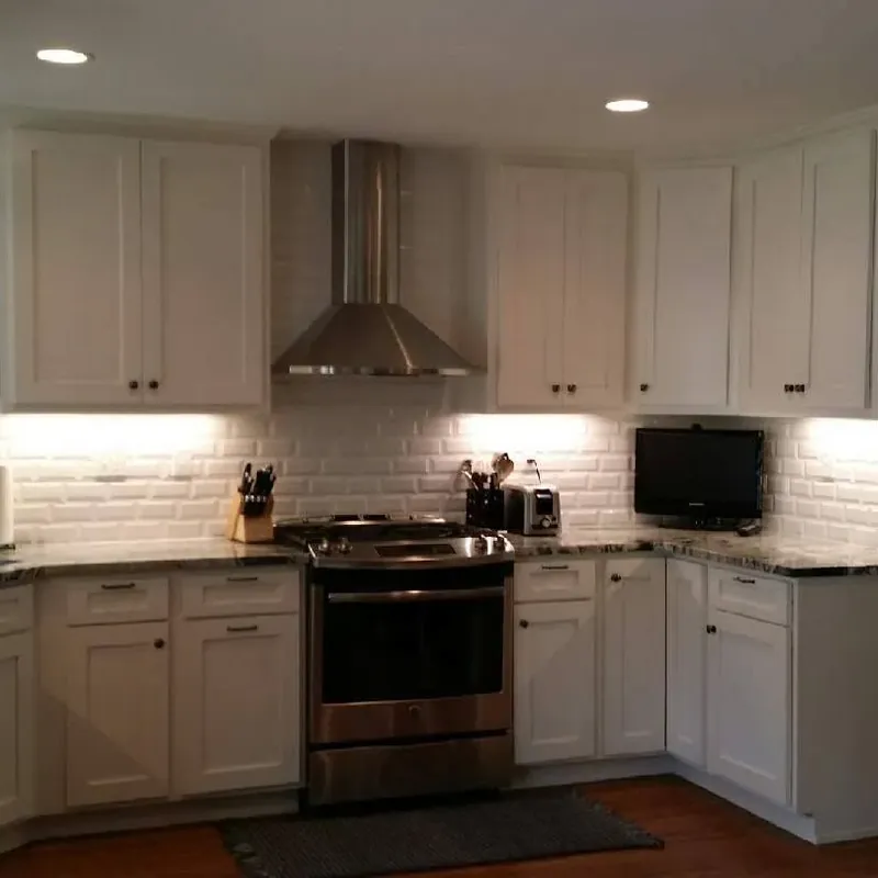 Finished white kitchen with undercabinet lights and stainless range, C&A Roofing & Construction