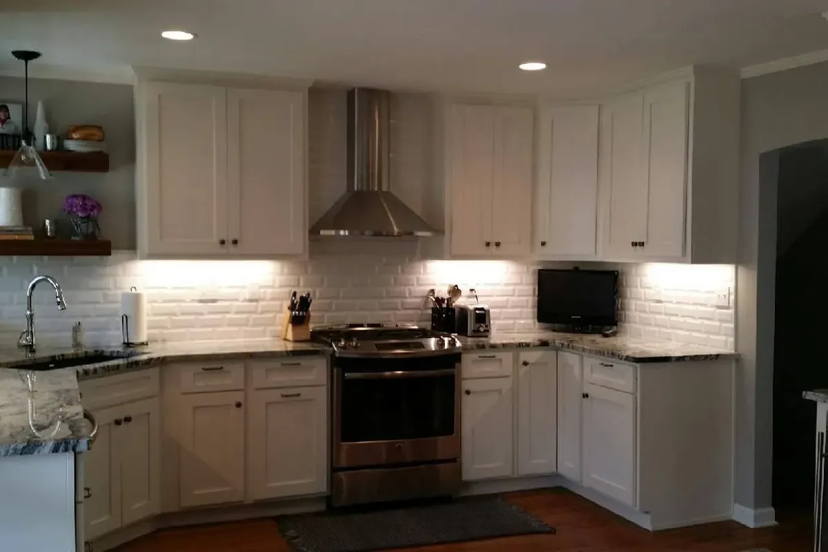Finished white kitchen with undercabinet lights and stainless range, C&A Roofing & Construction