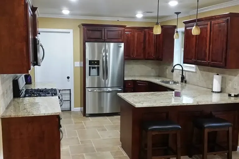 Dark cherry cabinets with island, stools and stainless fridge, C&A Roofing & Construction