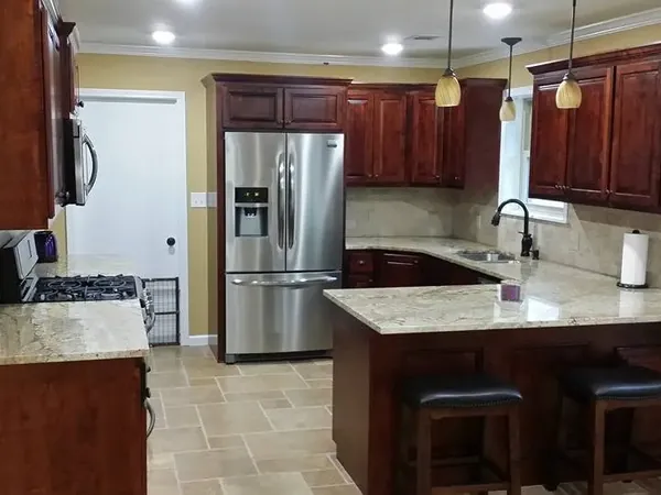 Dark cherry cabinets with island, stools and stainless fridge, C&A Roofing & Construction