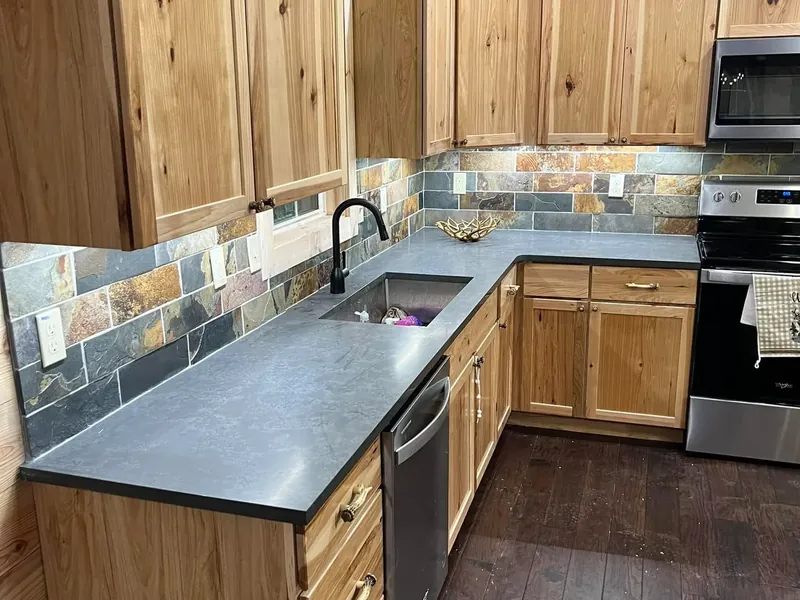 Rustic wood cabinets, slate backsplash, dark counters, C&A Roofing & Construction