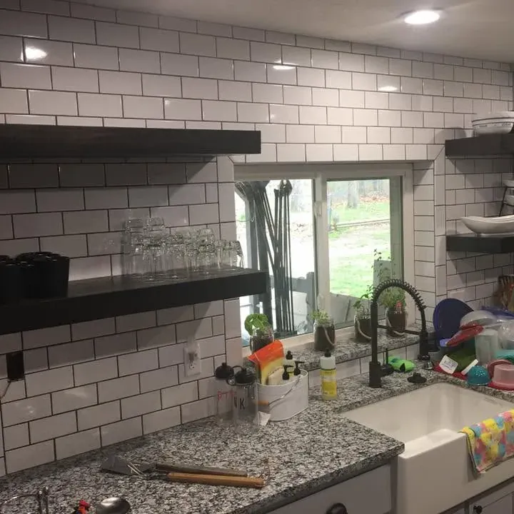 Subway tile backsplash with black floating shelves and farmhouse sink, C&A Roofing & Construction
